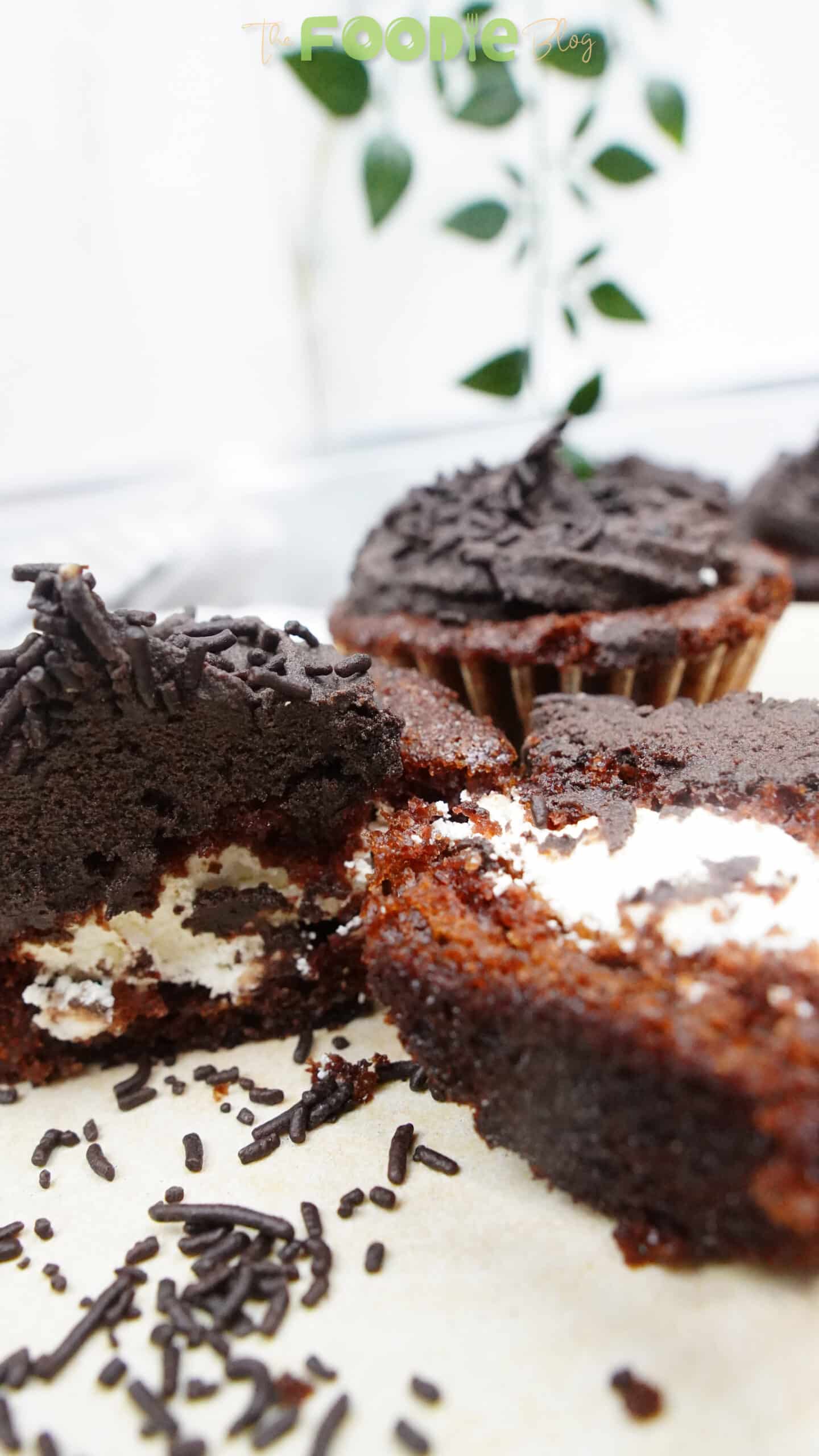 Frosted chocolate cupcakes with ganache and chocolate sprinkles on a light background