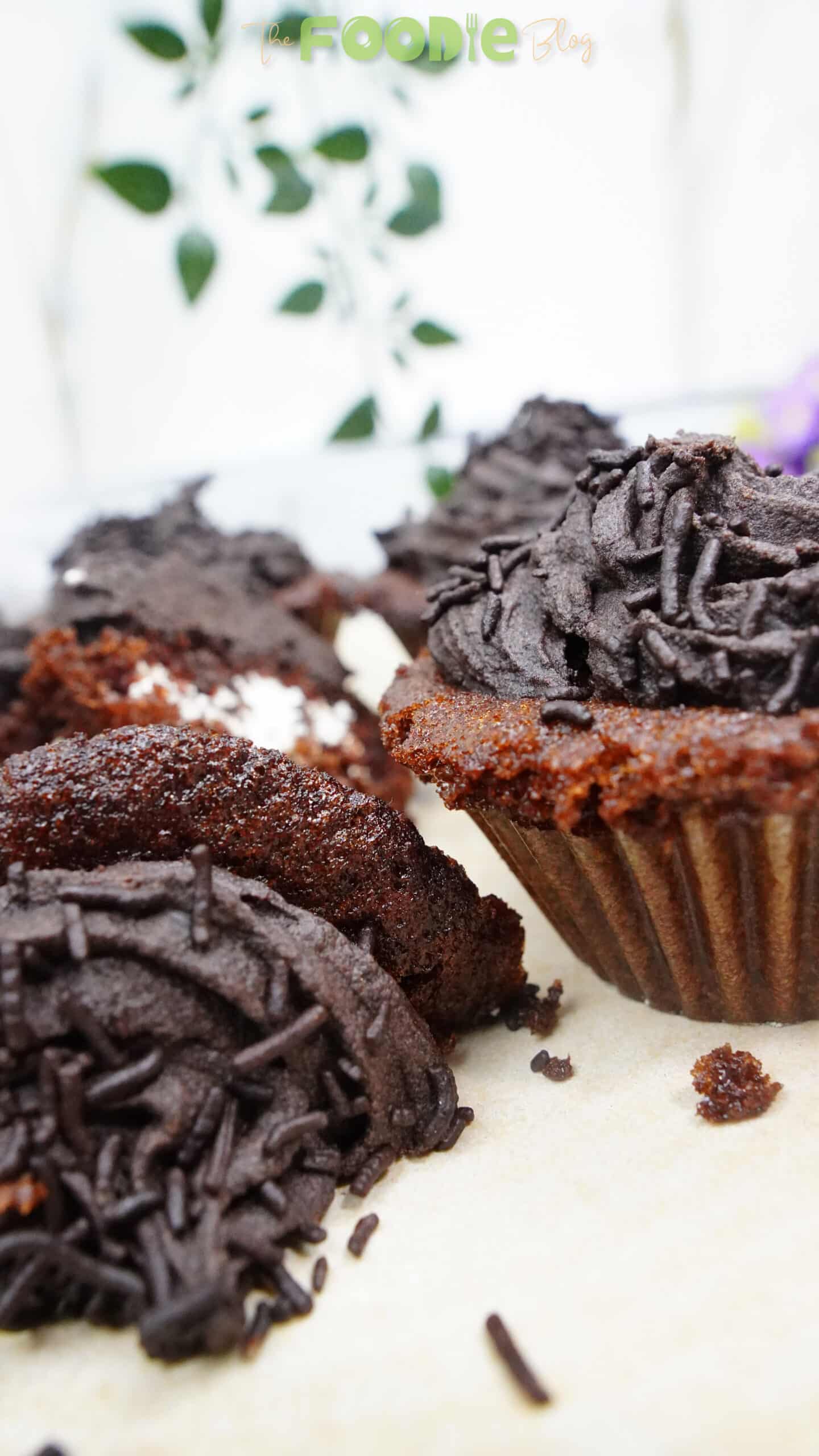 Close-up of chocolate cupcakes filled with cream and topped with chocolate ganache and sprinkles