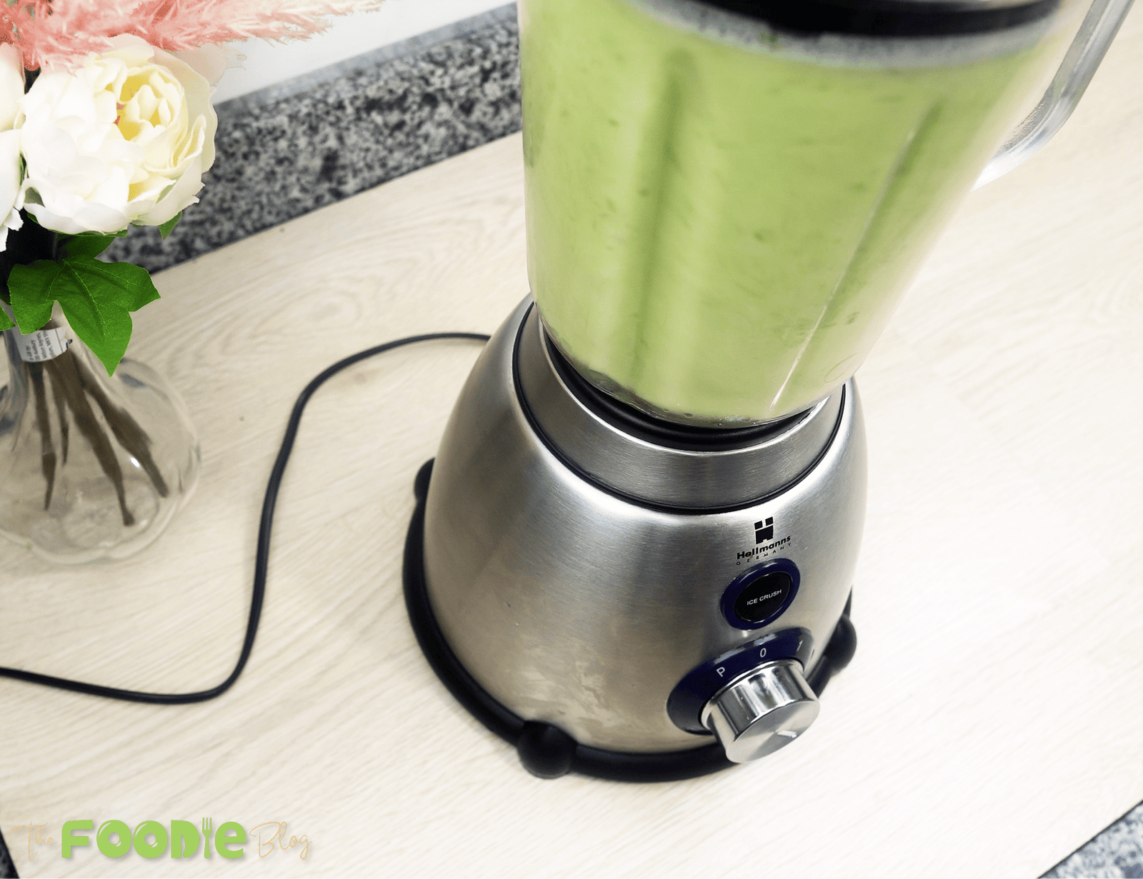 Blender running with a smooth pale-green cucumber lemonade mixture