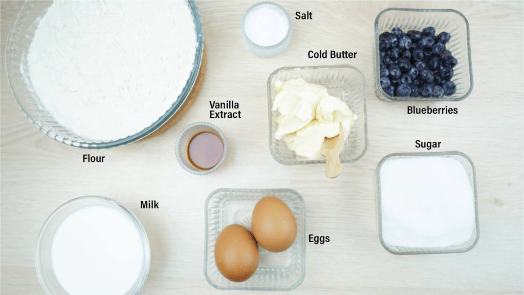 Blueberry cake ingredients including flour, sugar, cold butter, milk, eggs, vanilla, salt, and blueberries