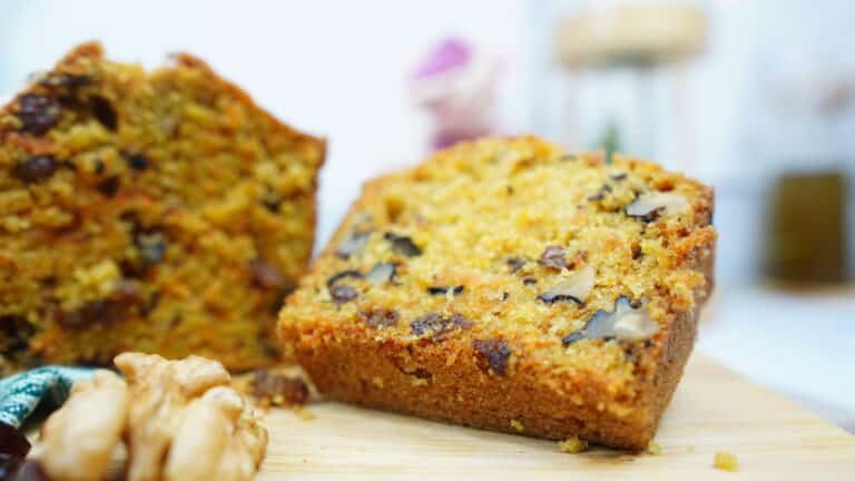 slice of carrot cake loaf on a board with walnuts and raisins