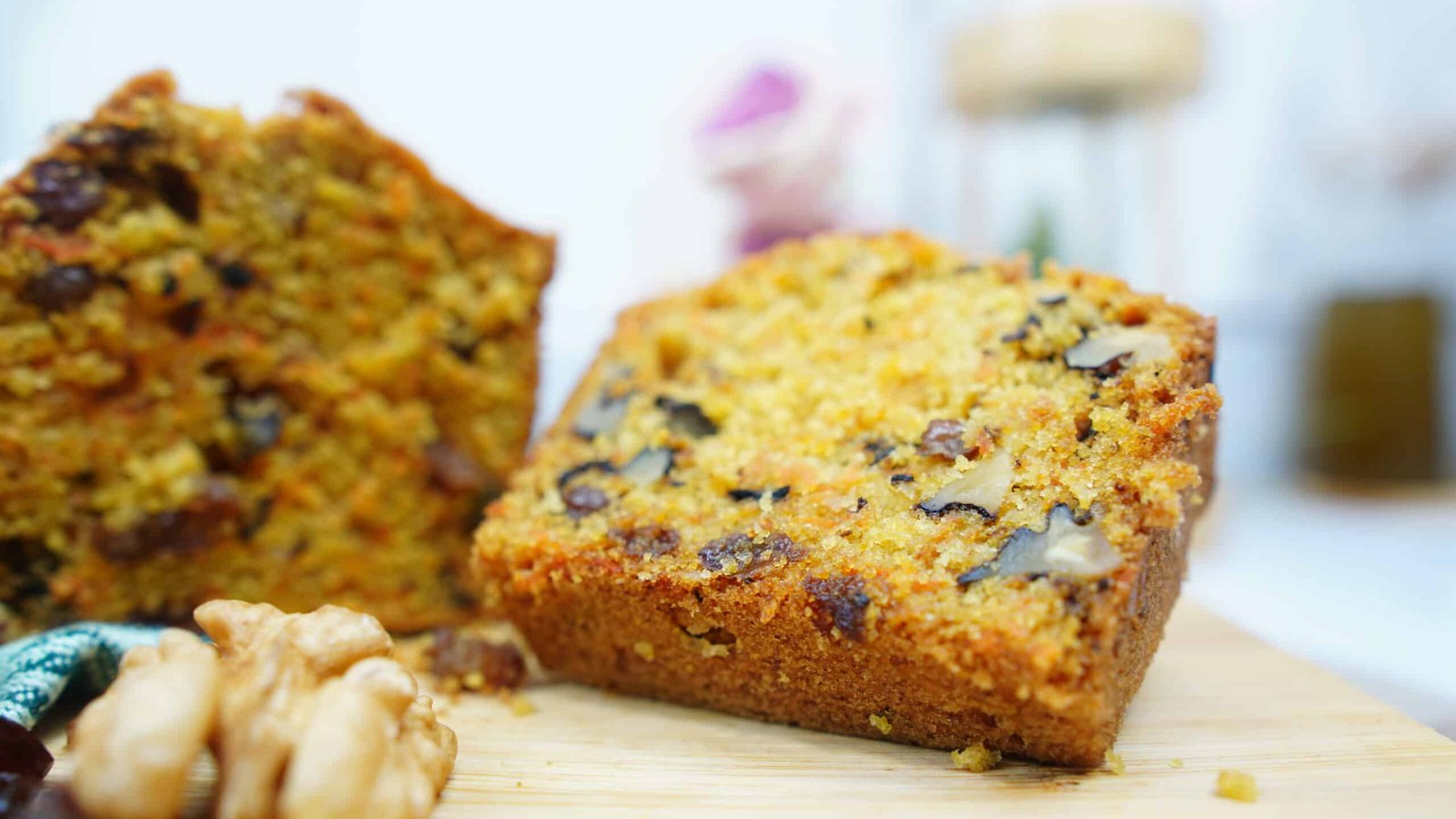 slice of carrot cake loaf on a board with walnuts and raisins