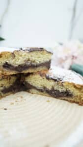 Whole chocolate filled cake dusted with powdered sugar, with one slice removed.
