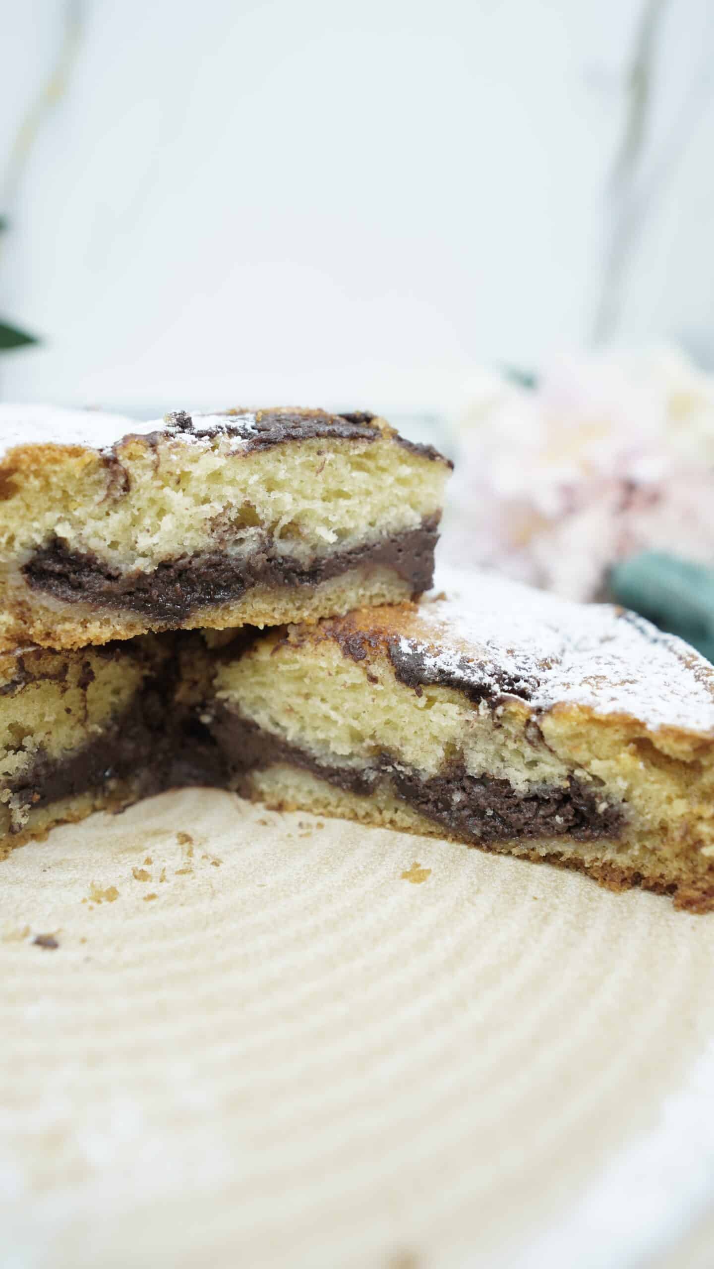 Whole chocolate filled cake dusted with powdered sugar, with one slice removed.