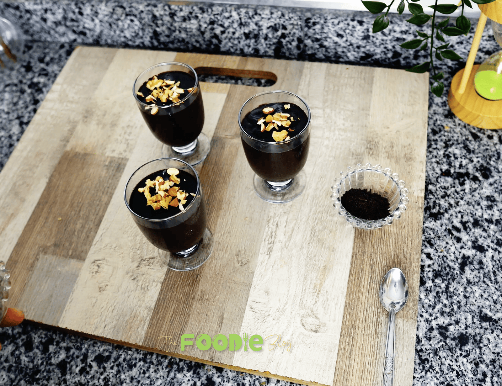A glass of dark, creamy chocolate pudding topped with chopped walnuts.