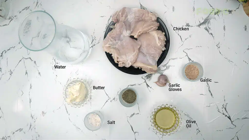 Ingredients for garlic chicken thighs including chicken, butter, oil, garlic, salt, pepper, and water on a marble surface