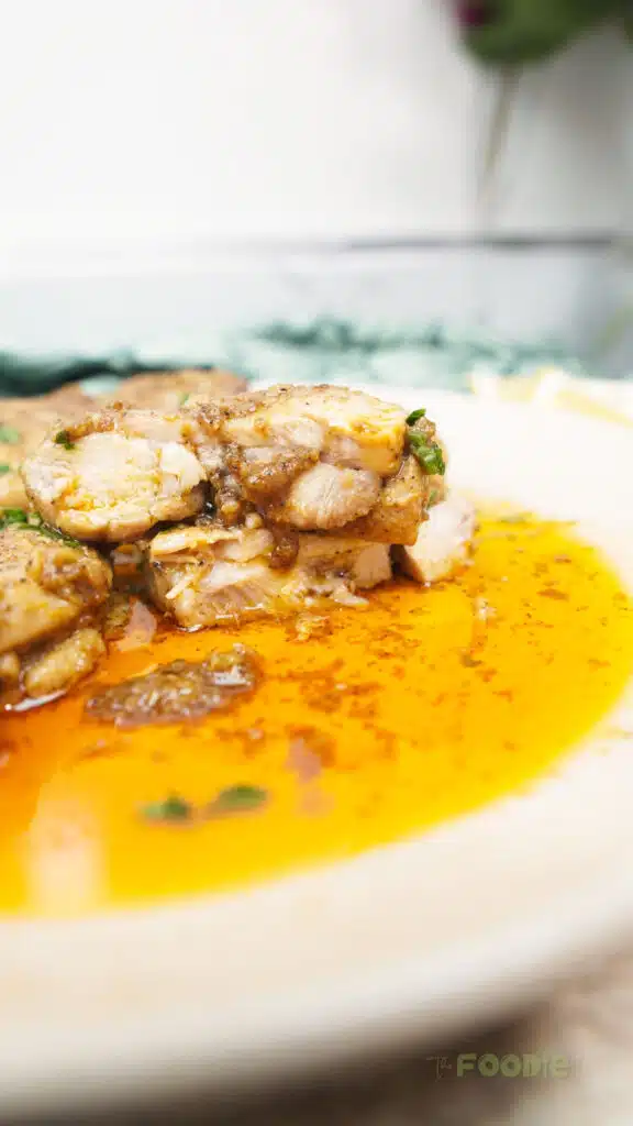 Close-up of chicken thighs stacked with golden garlic butter sauce pooling on the plate