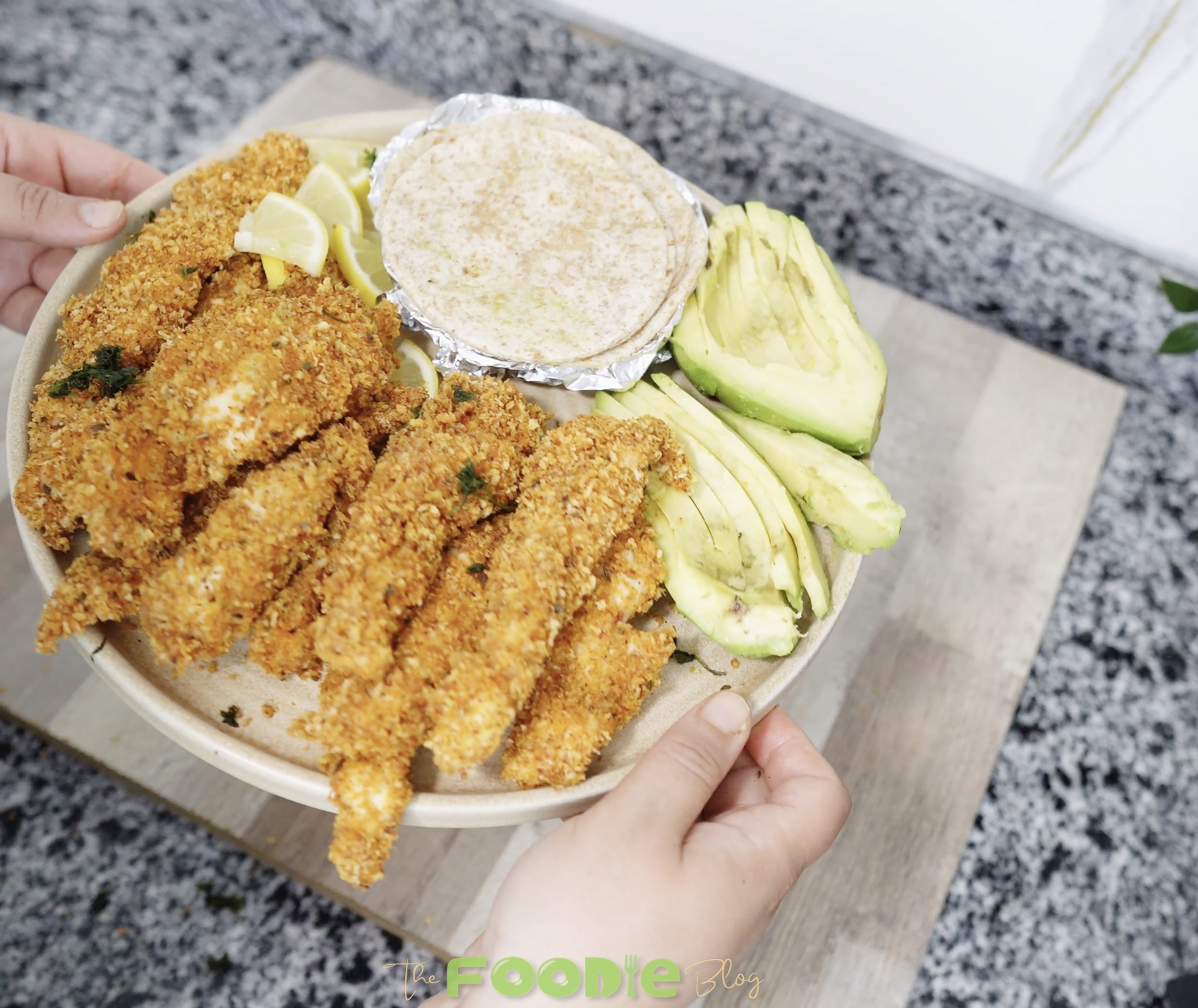 hand holding a tortilla taco filled with crunchy chicken strip and avocado