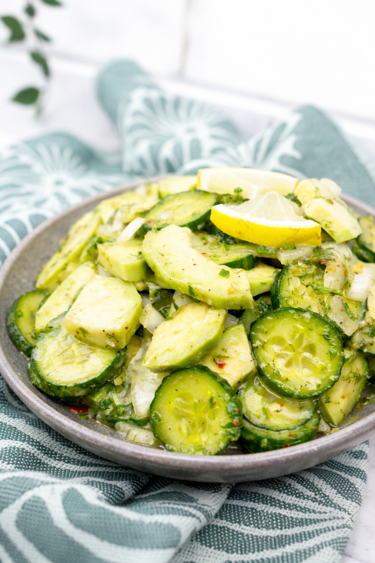 Fresh cucumber avocado salad with lemon slices, dill and onion in a bowl
