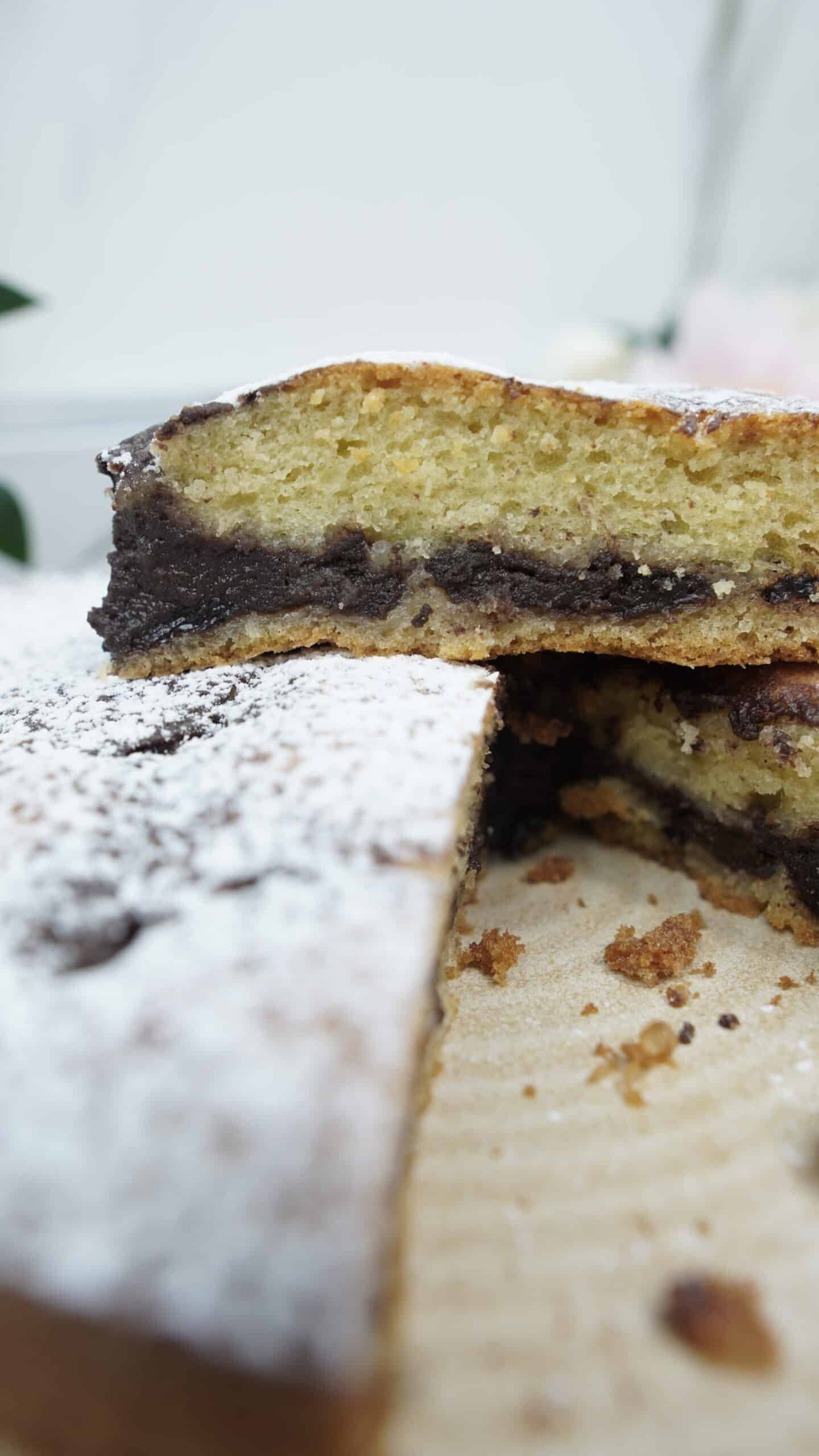 Whole chocolate filled cake dusted with powdered sugar, with one slice removed.