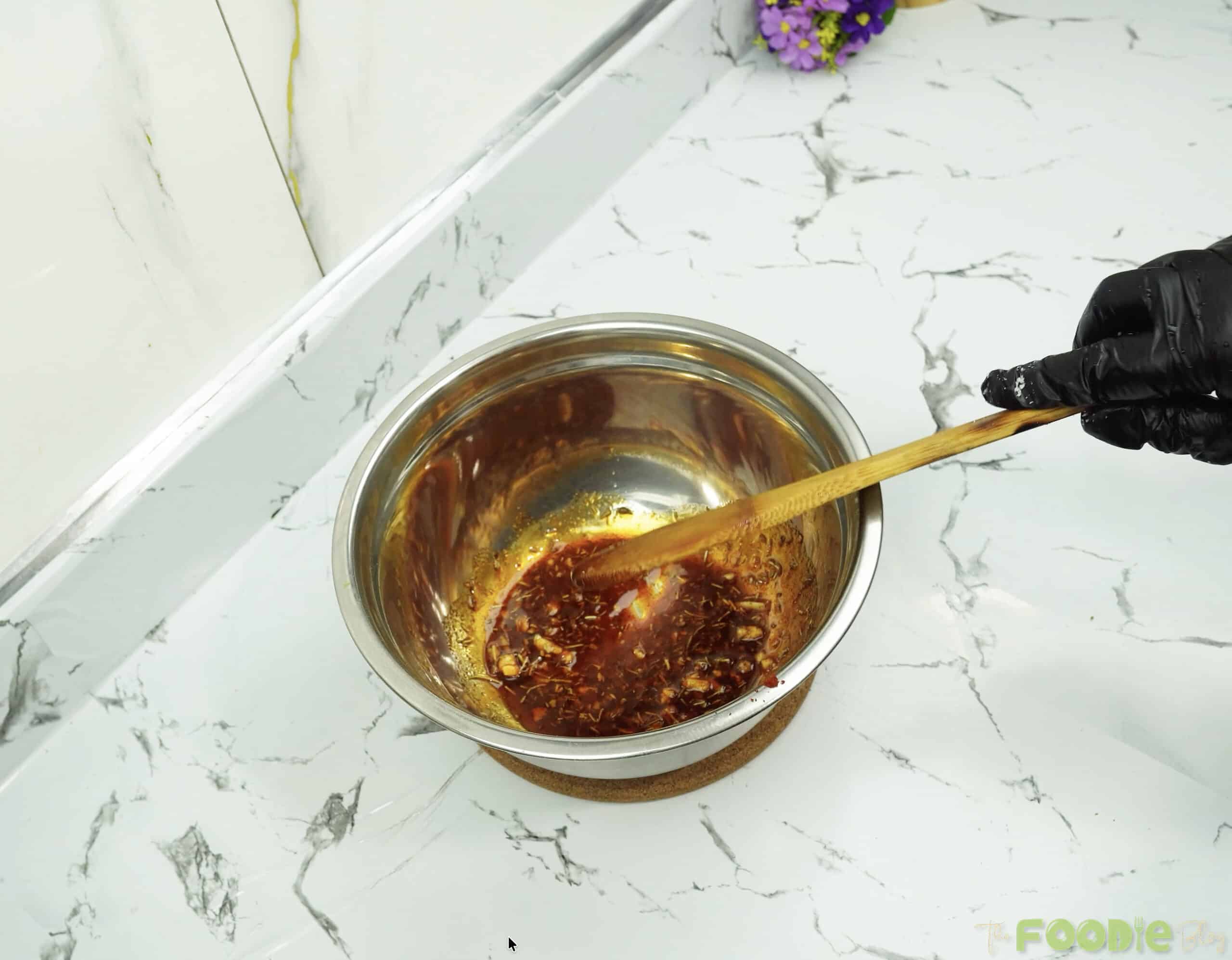 Seasoned olive oil mixture in a bowl being stirred with a spoon