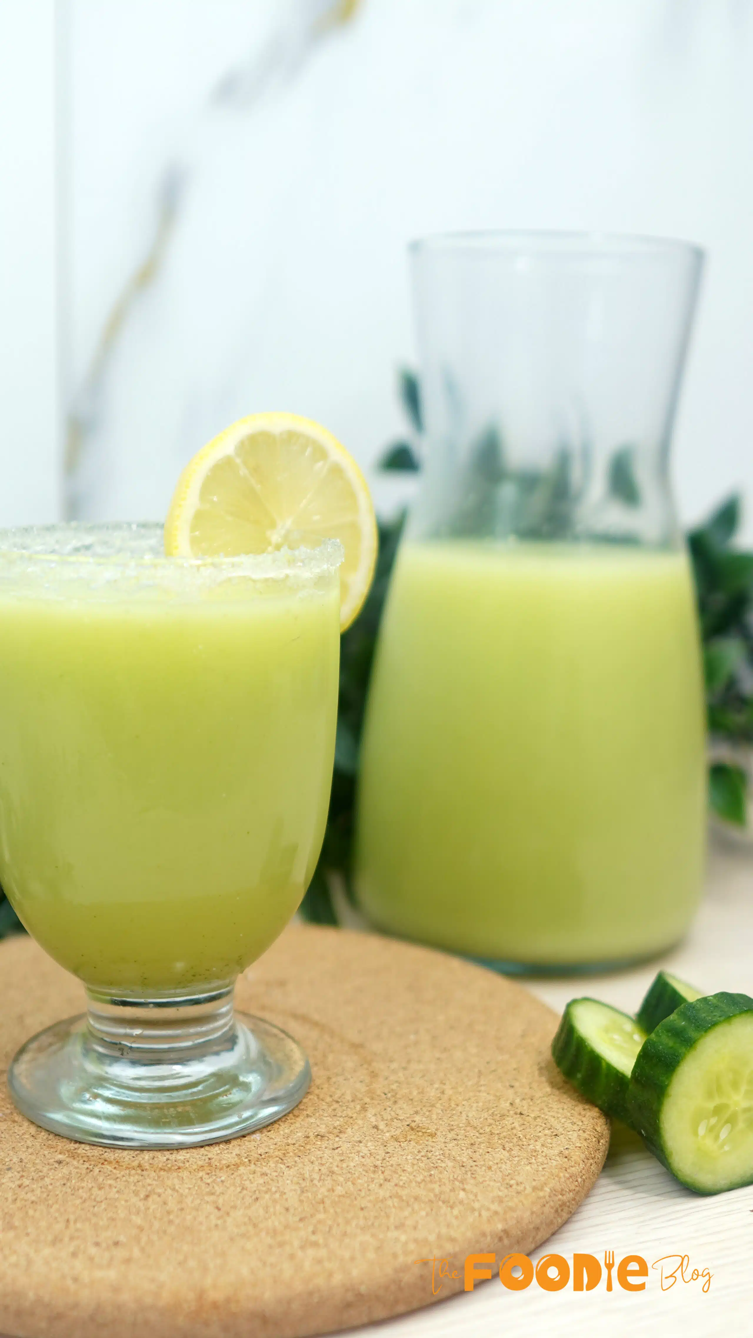 Creamy cucumber lemonade in a glass with a lemon slice garnish and a pitcher in the background