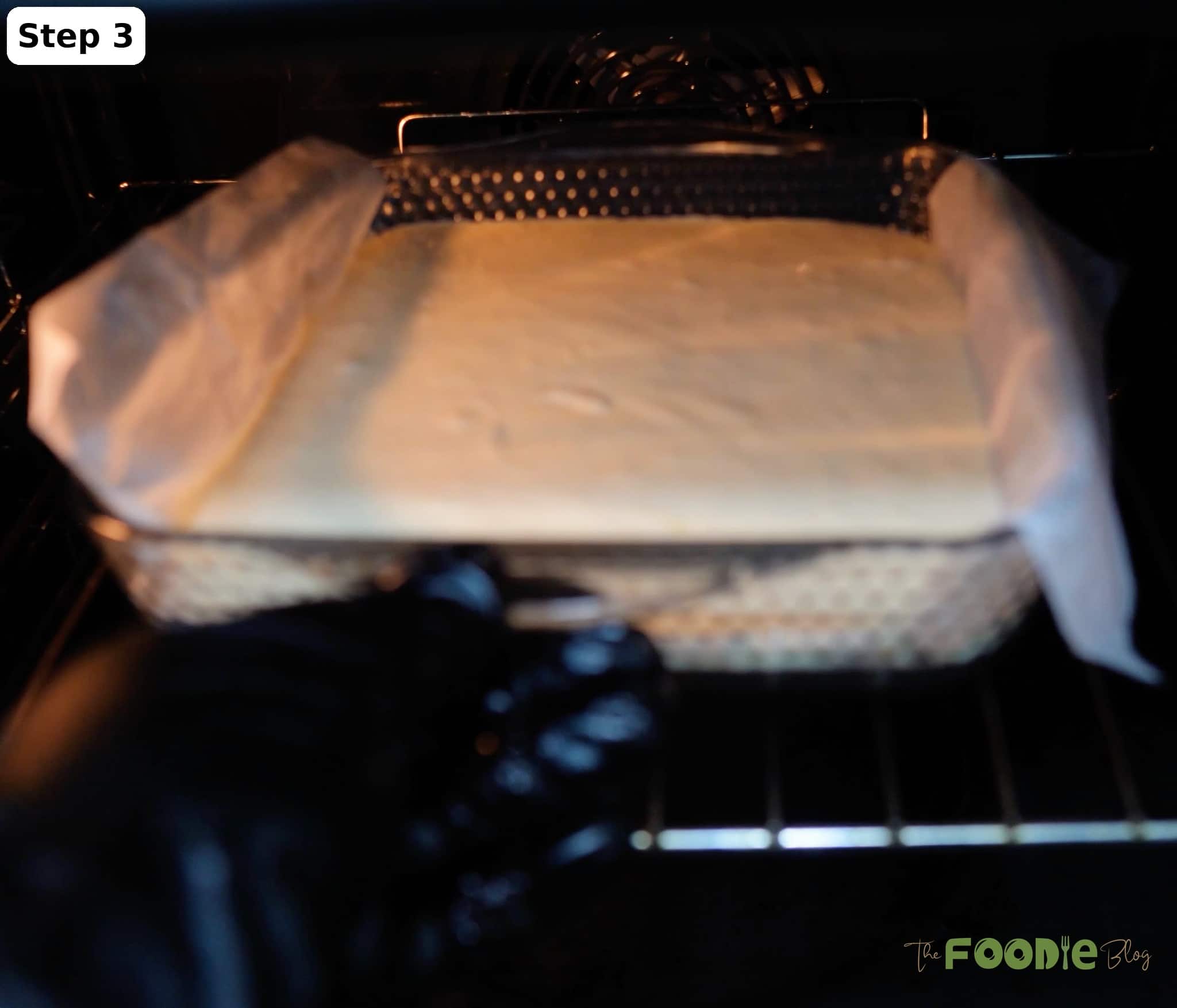Baking the cheesecake layer in a parchment-lined pan inside the oven