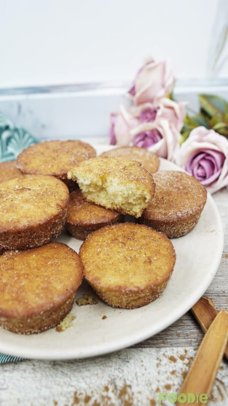 Mini cinnamon muffins on a plate with one muffin broken open to show the inside