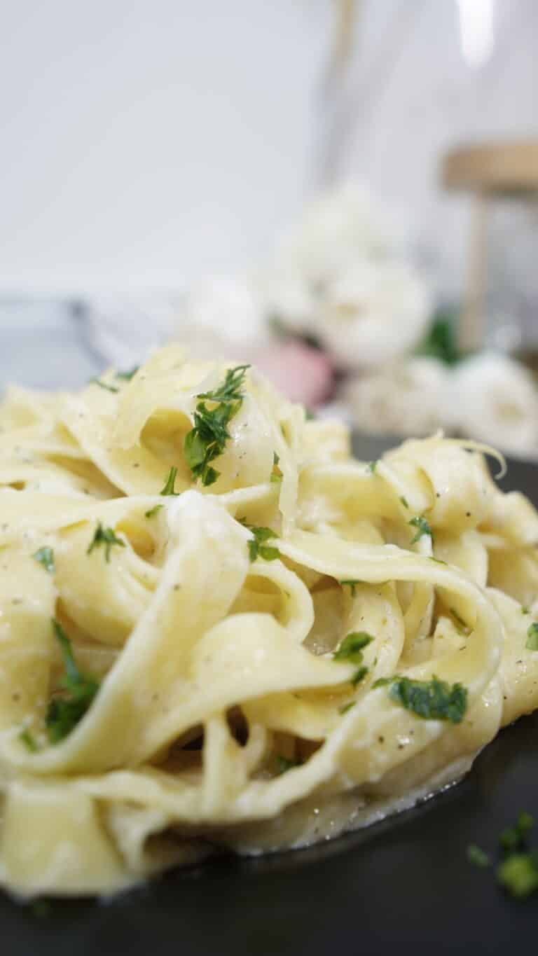 Tagliatelle coated in creamy garlic parmesan sauce close-up