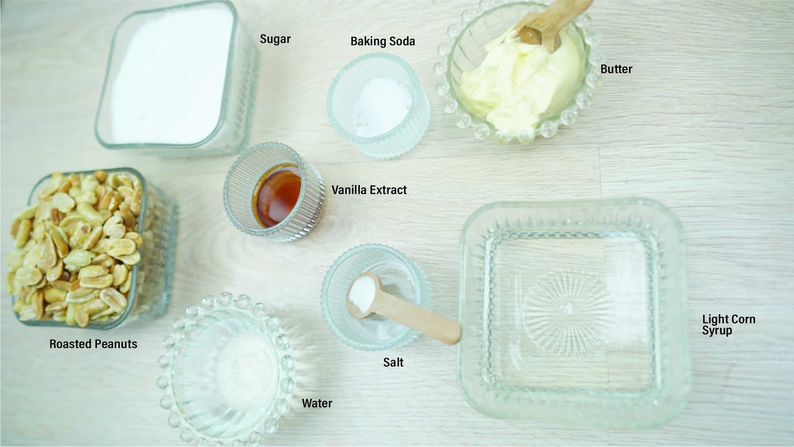 Measured ingredients for peanut brittle including sugar, corn syrup, butter, peanuts, vanilla, salt, and baking soda