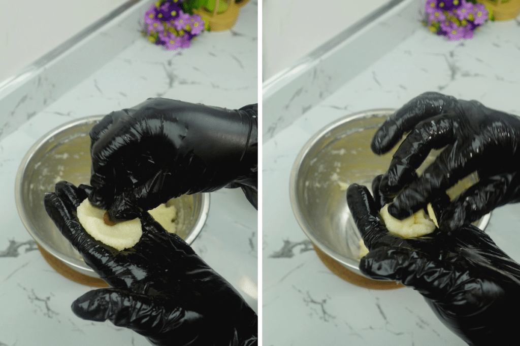Hands sealing an almond inside the coconut mixture and rolling it into a ball