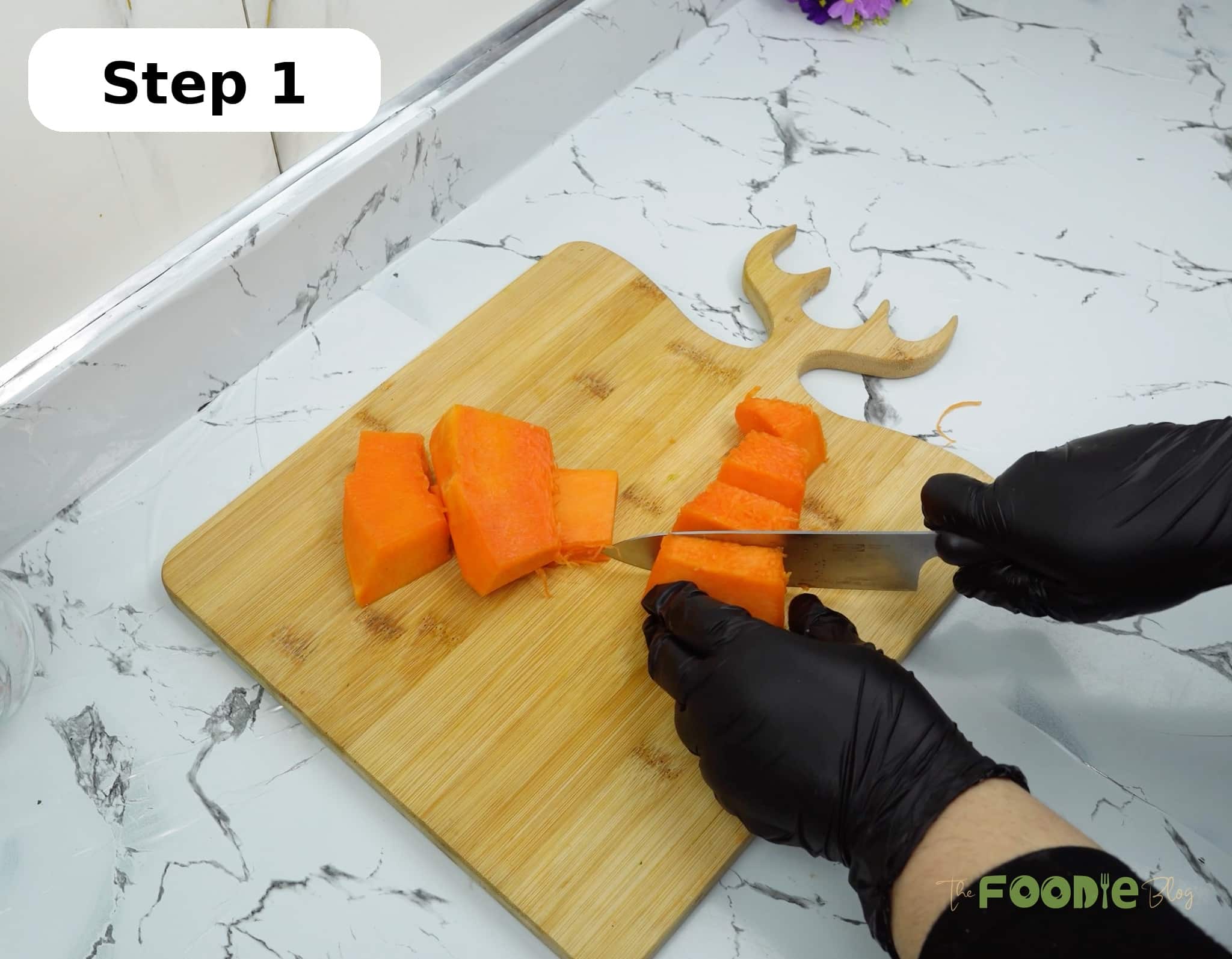 Hands cutting peeled pumpkin into pieces on a wooden cutting board