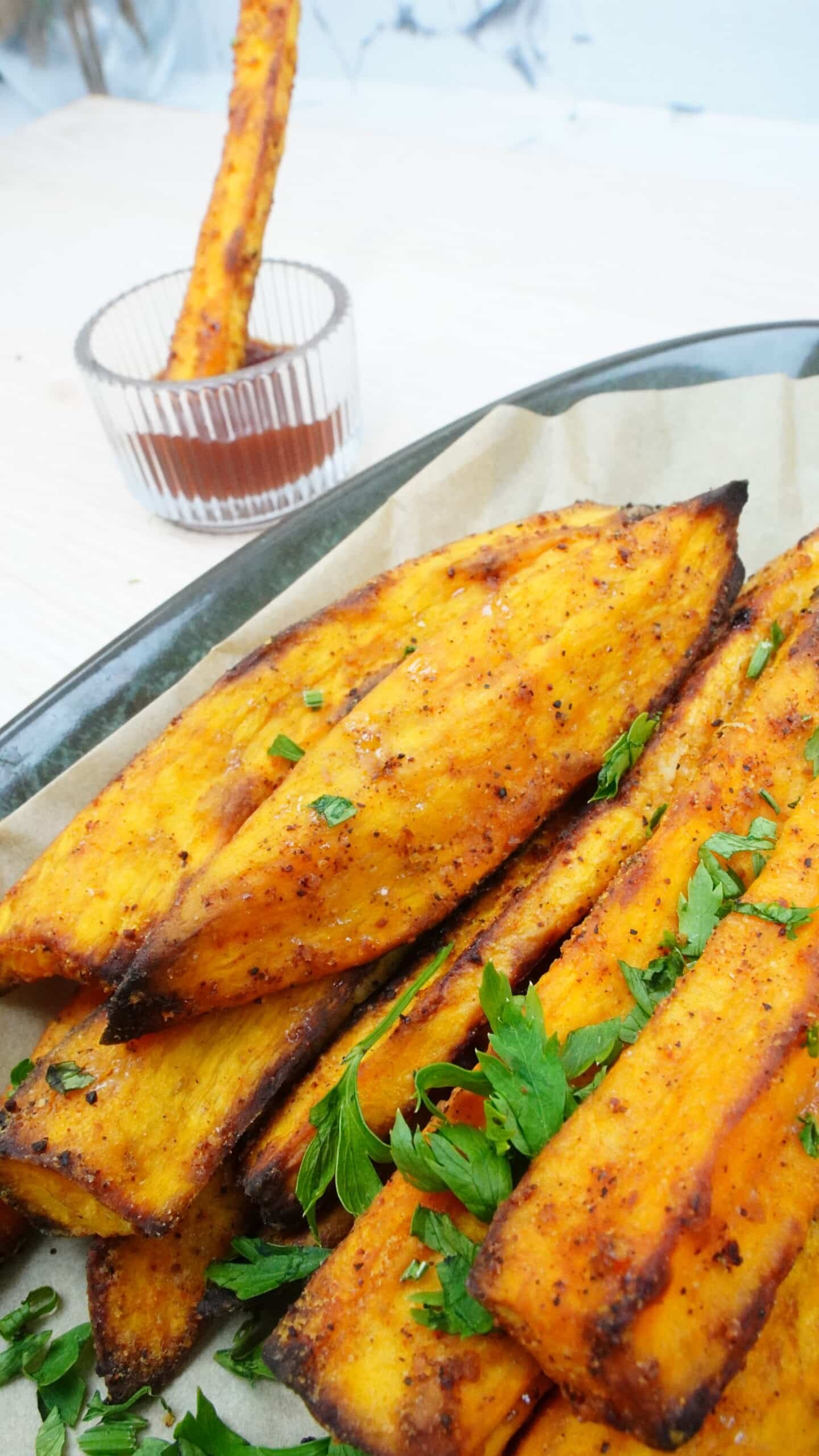 Close-up of baked sweet potato fries with chopped herbs on top