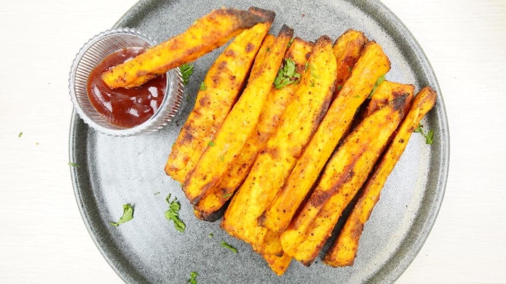Sweet potato fries served on a plate with ketchup on the side