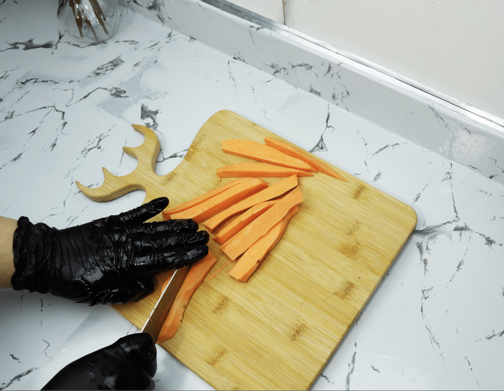 Cutting sweet potatoes into fries on a cutting board