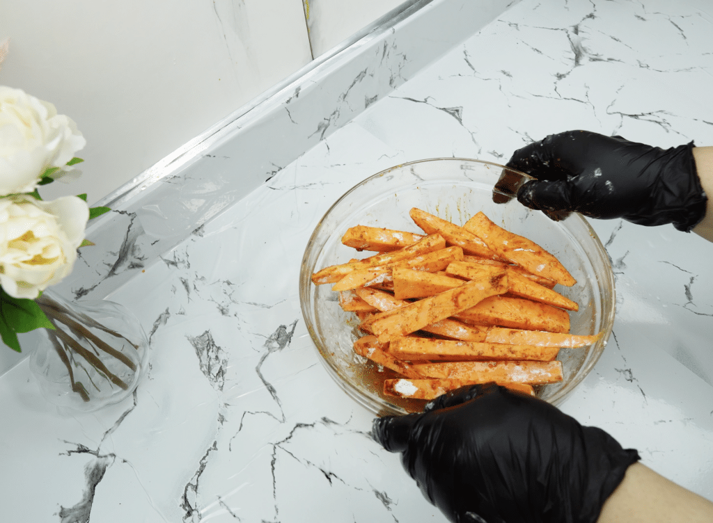 Sweet potato fries tossed with spices in a glass bowl
