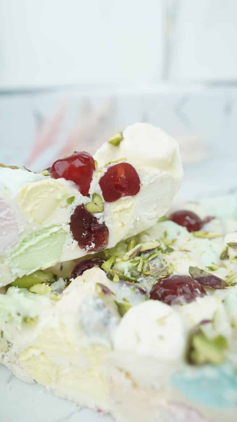 close up of a rocky road piece with cherries marshmallows and pistachios