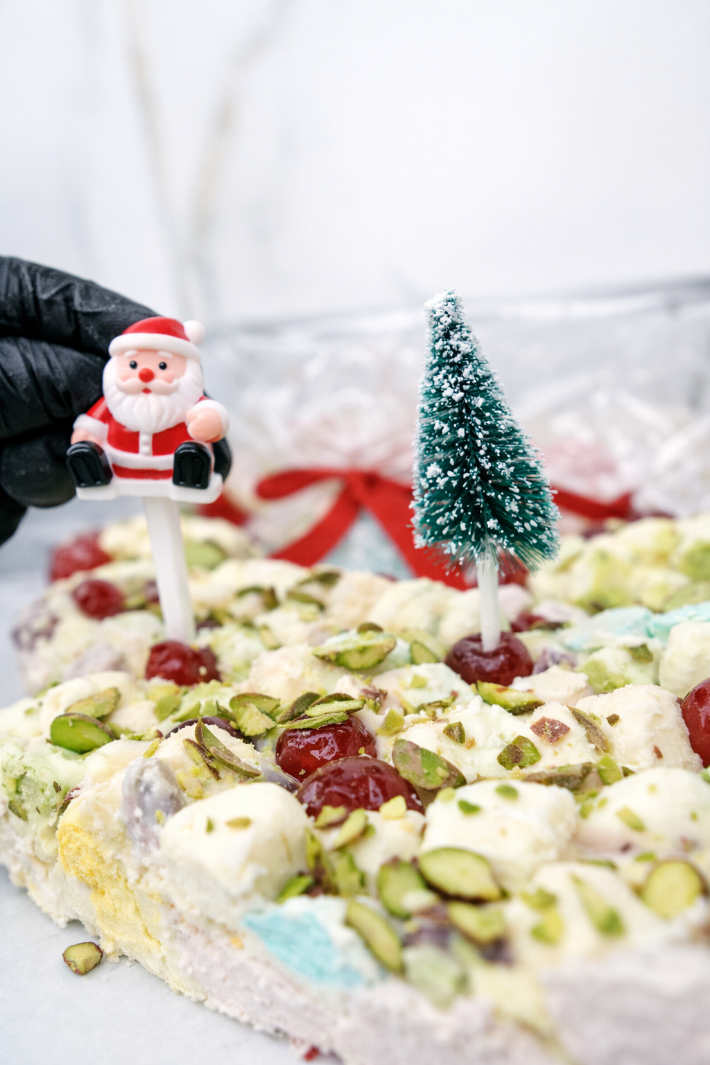 White Christmas rocky road topped with glacé cherries and pistachios with Christmas decorations in the background