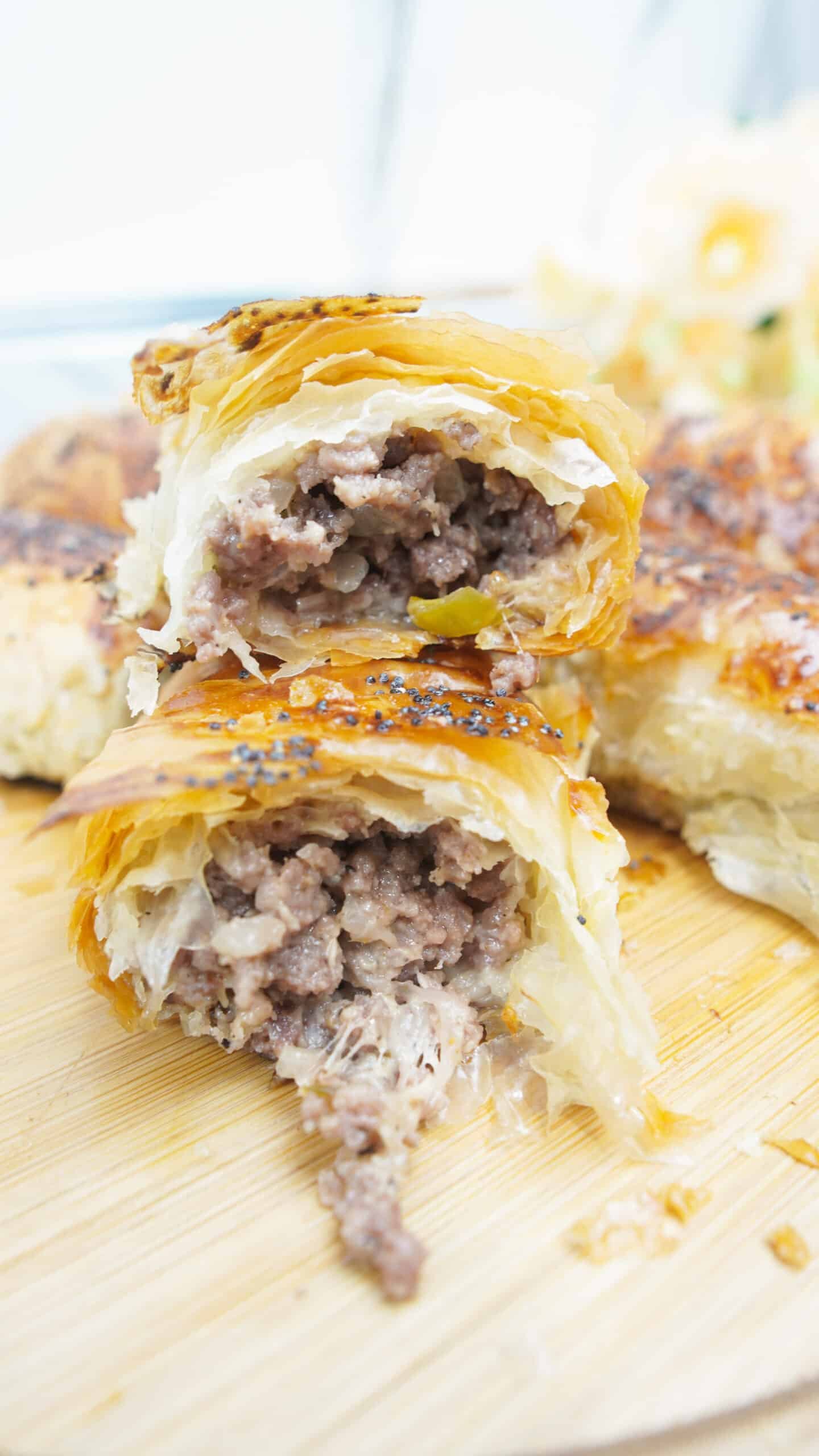 Cut open crispy minced meat cigar showing juicy meat and cheese filling