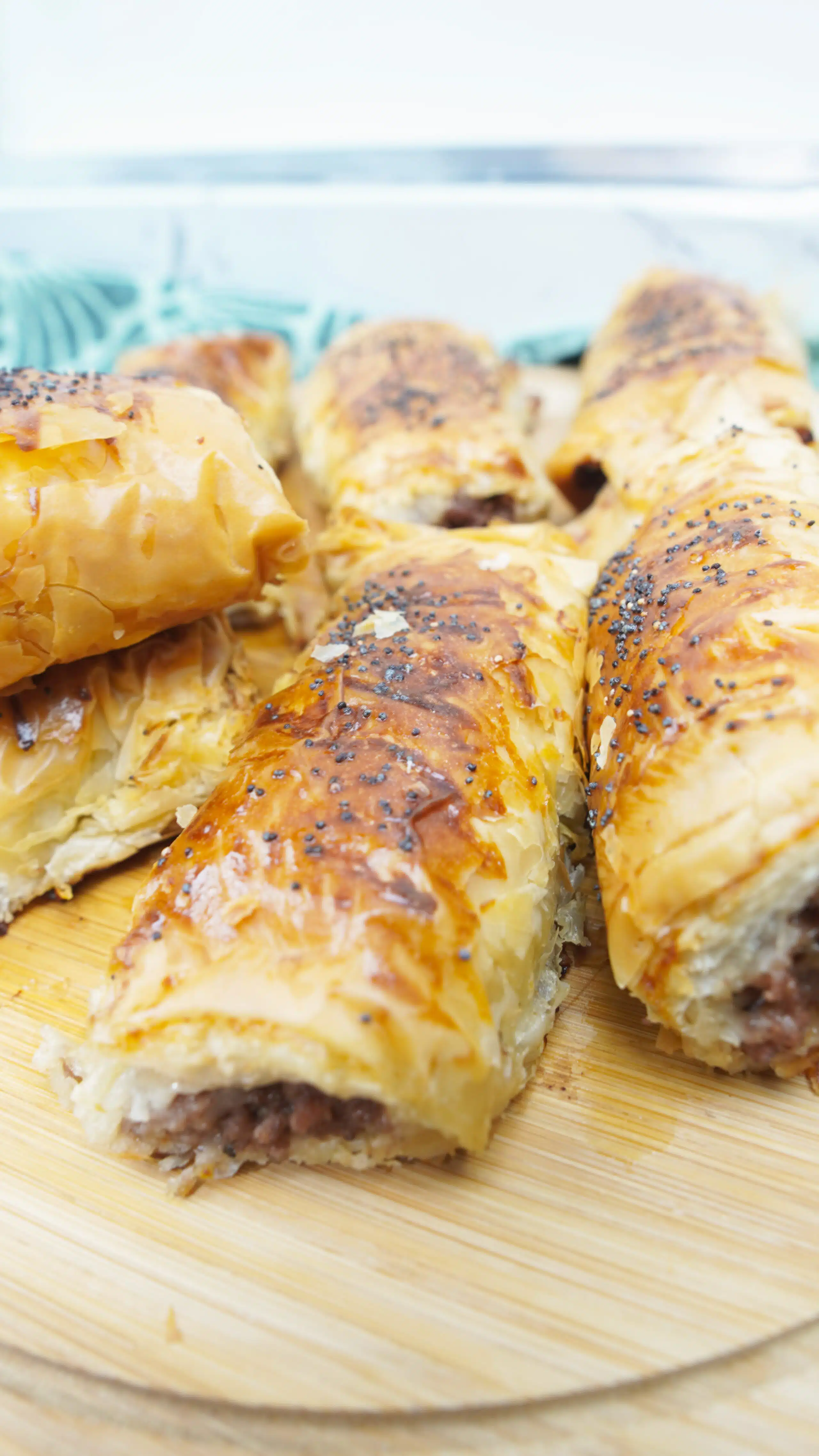 Hand holding a crispy minced meat cigar with poppy seeds on top