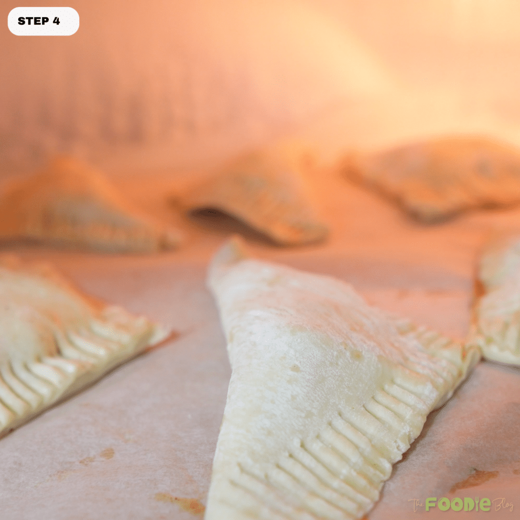 Unbaked apple turnovers on a lined baking sheet ready to chill before baking