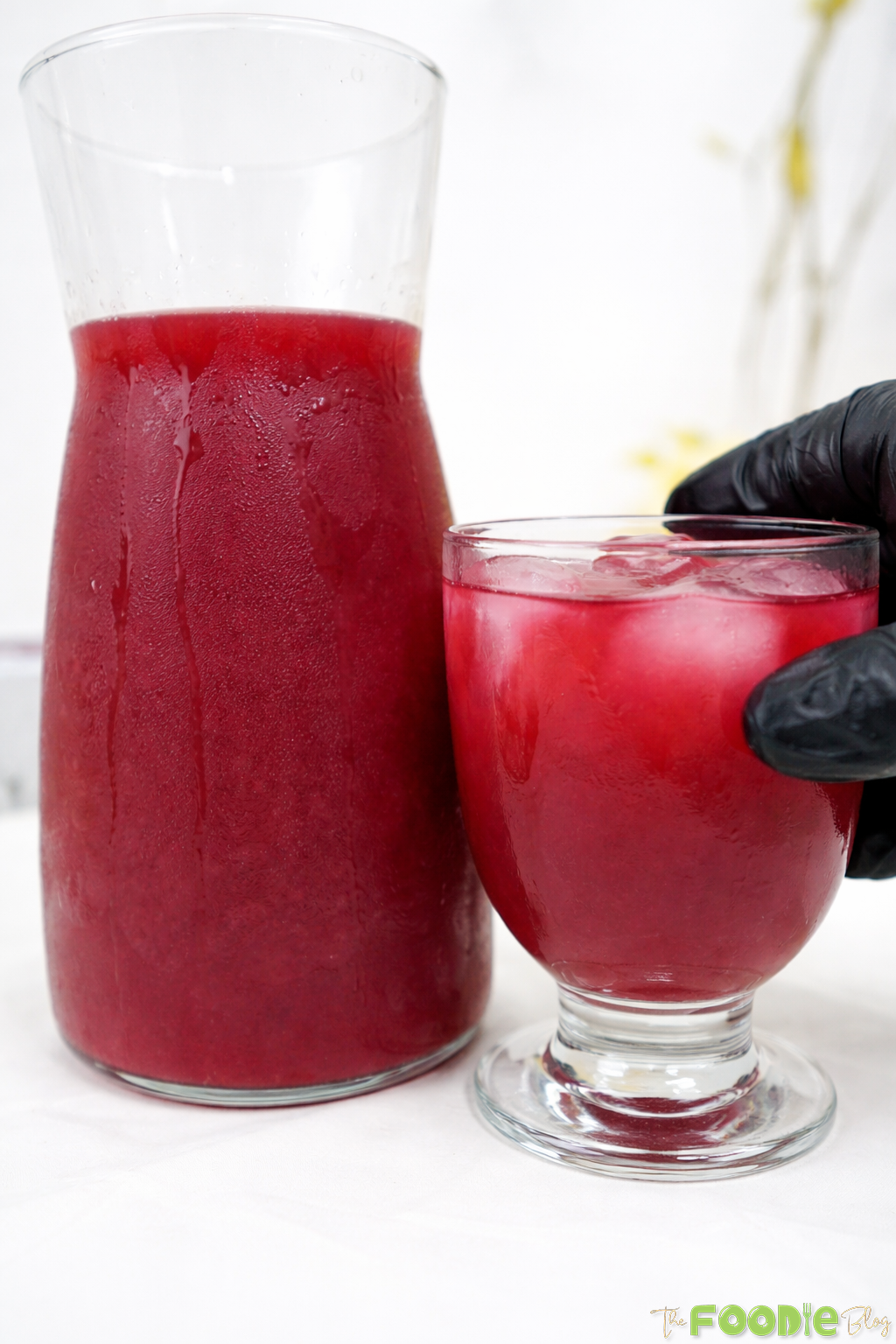 Beetroot juice with carrot, banana, and orange juice served in a glass with a chilled carafe.