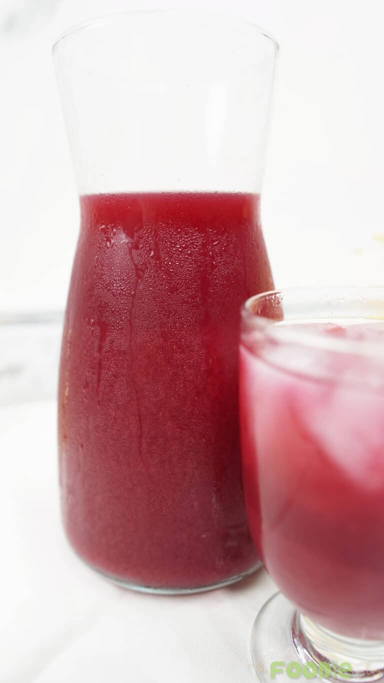 Close-up of a chilled carafe filled with beetroot juice with a glass partially visible