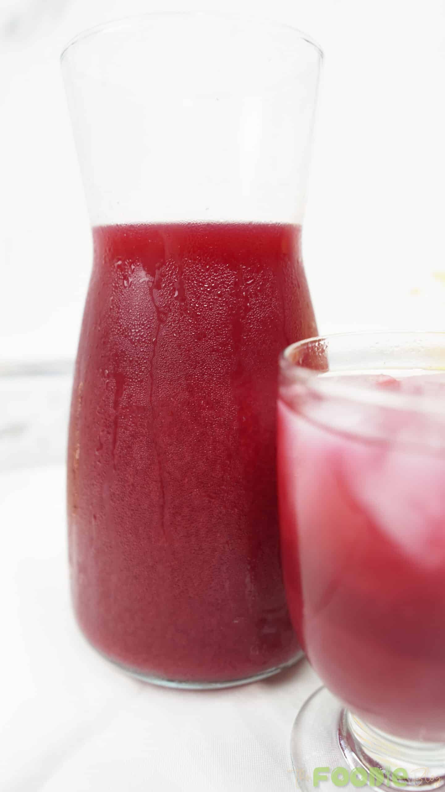 Close-up of a chilled carafe filled with beetroot juice with a glass partially visible