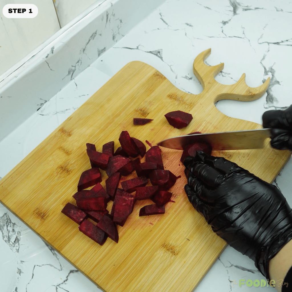 Chopped beetroot pieces on a cutting board being sliced with a knife