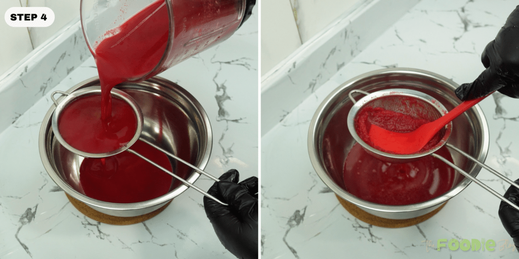 Red blended juice being poured through a fine-mesh strainer into a bowl