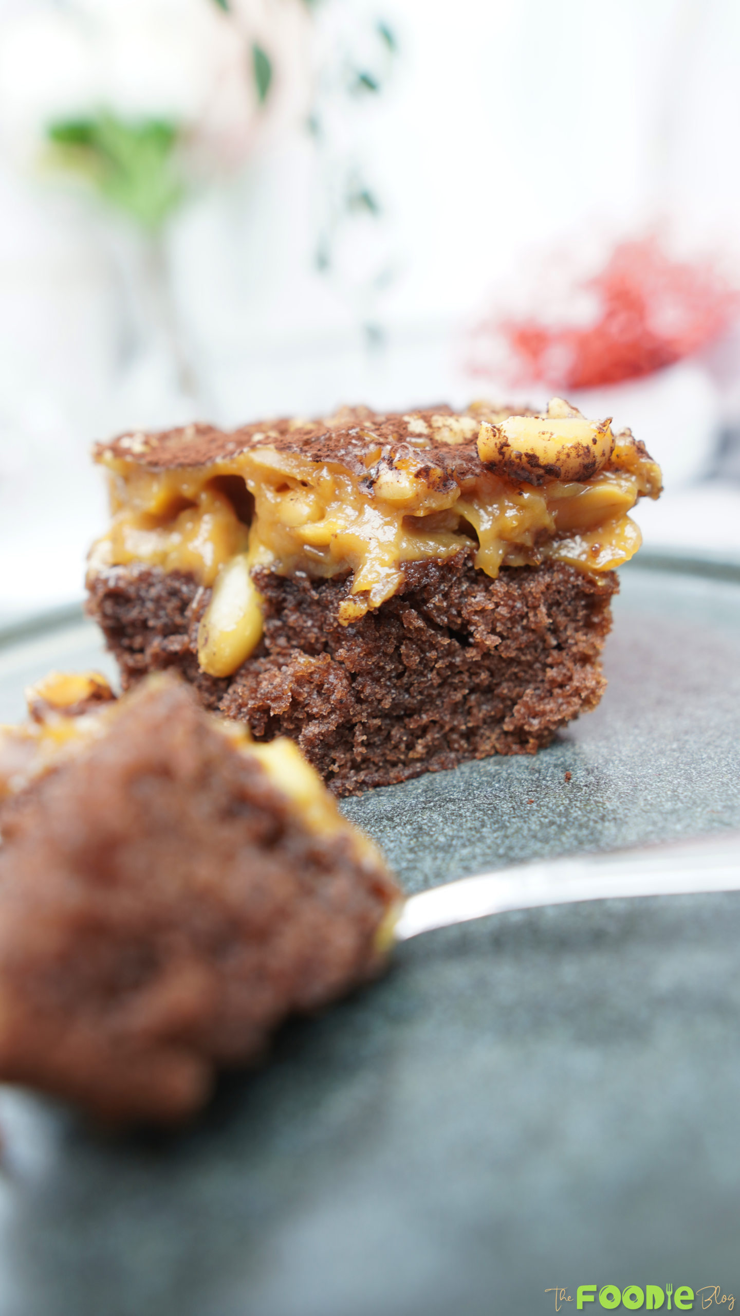 Close-up of a chocolate cake bar topped with caramel and roasted peanuts