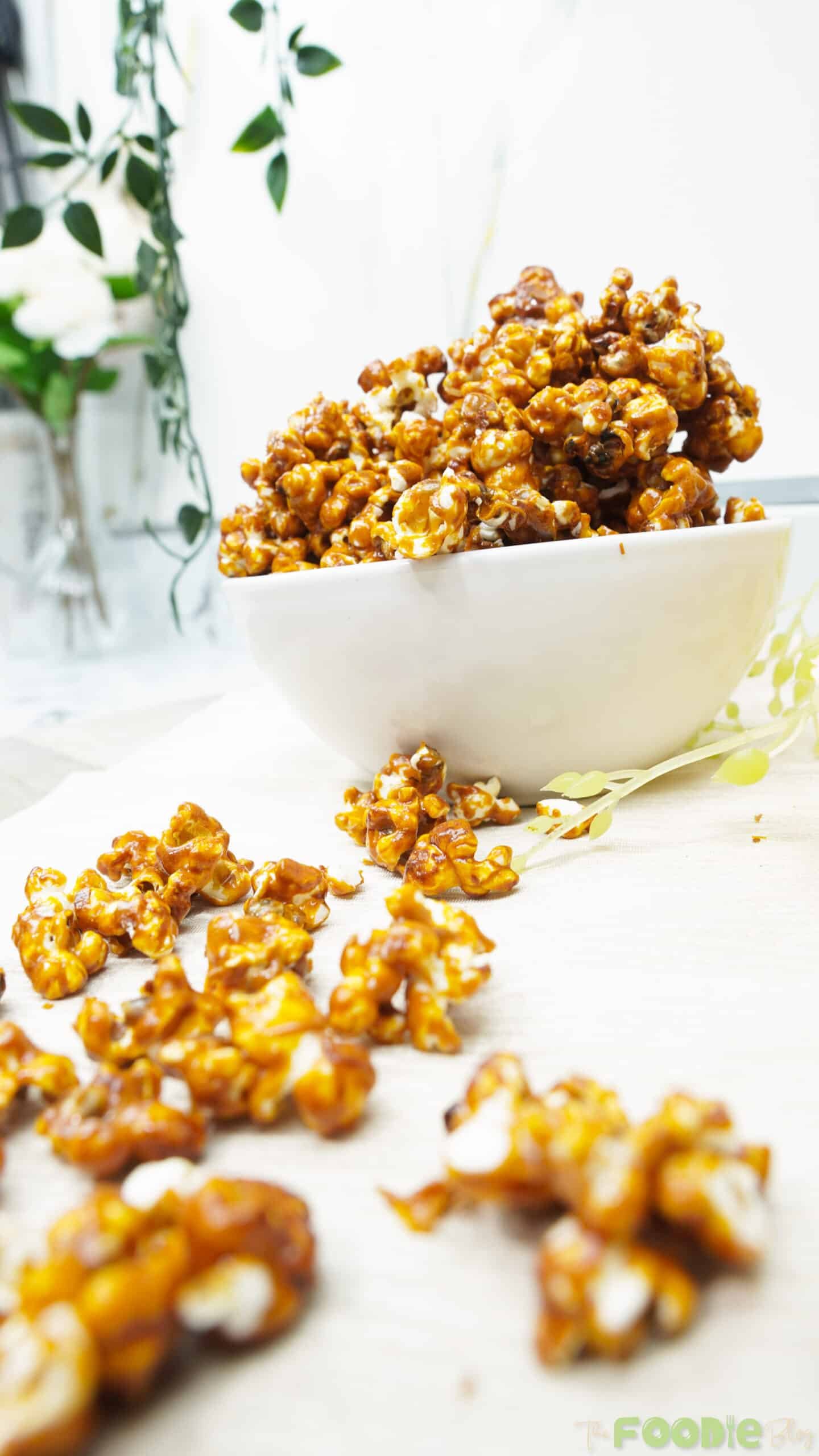 Bowl of caramel popcorn on a bright table with a soft, airy background