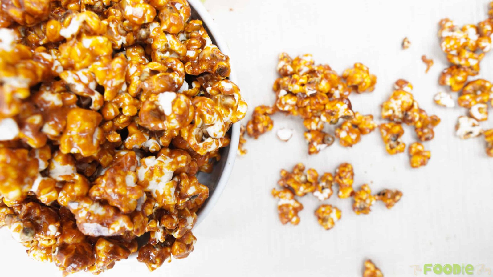 Top view of caramel popcorn with extra pieces scattered on a light surface
