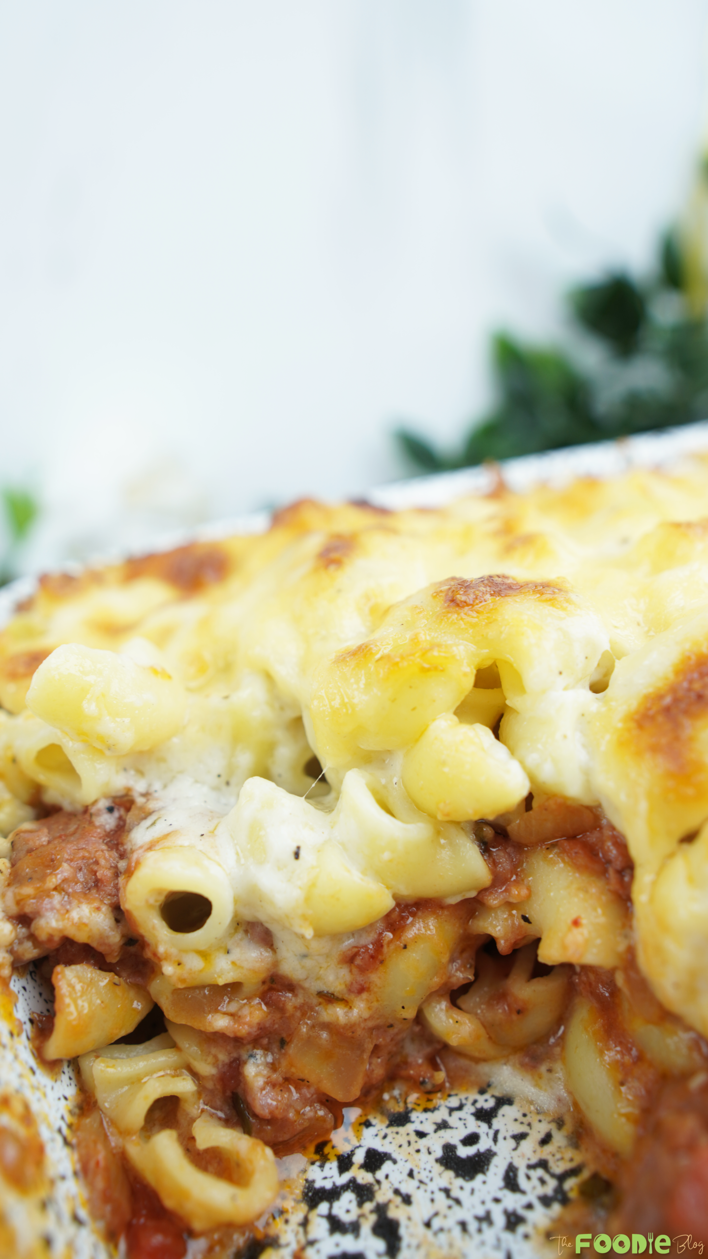 Close-up of cheesy baked pasta with beef and tomato sauce in a casserole dish