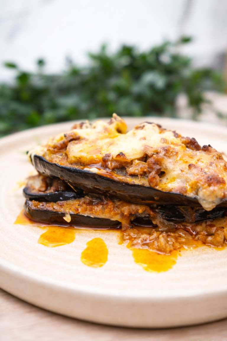 Close-up of cheesy beef-stuffed eggplant boats with melted mozzarella and saucy tomato-beef filling.