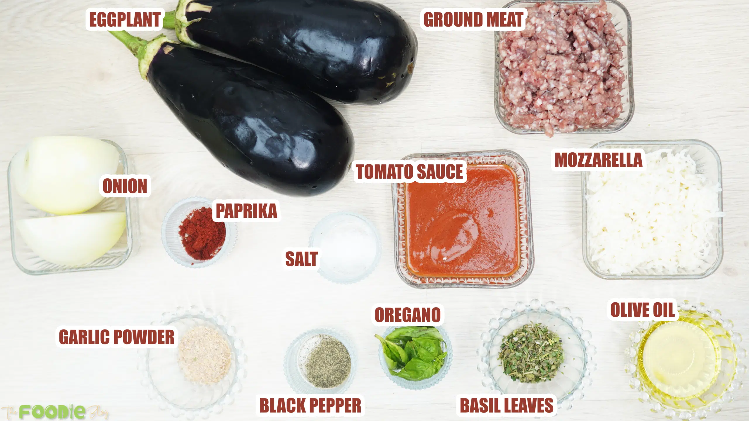 Ingredients for cheesy beef-stuffed eggplant boats including eggplant, ground meat, onion, tomato sauce, mozzarella, olive oil, and spices.