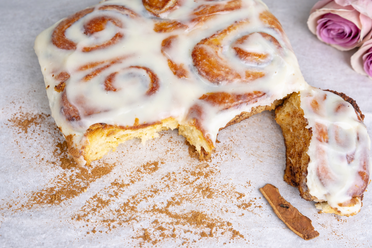 Fresh baked cinnamon rolls in a baking dish topped with cream cheese glaze.