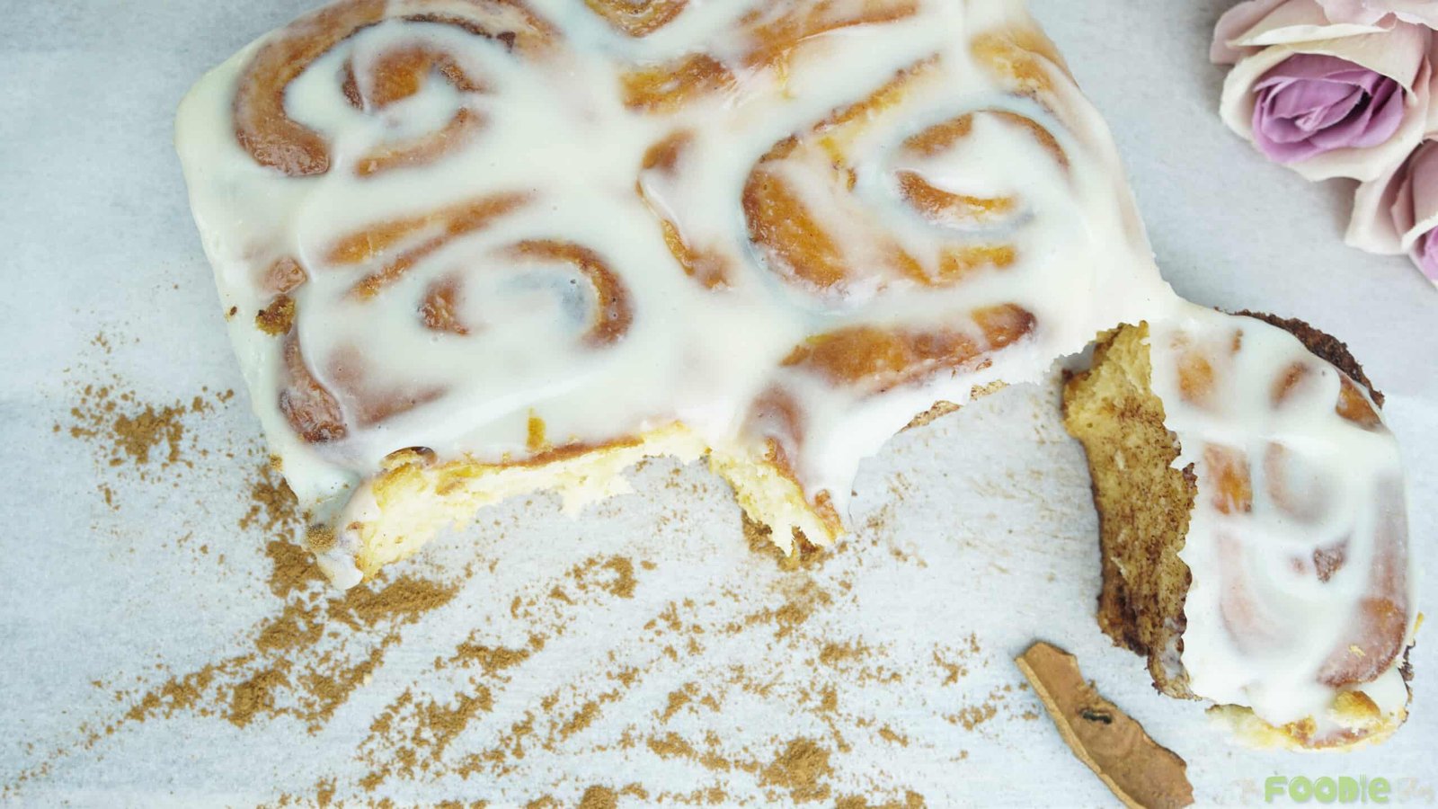 Top view of soft cinnamon rolls covered in cream cheese icing with one bite taken out