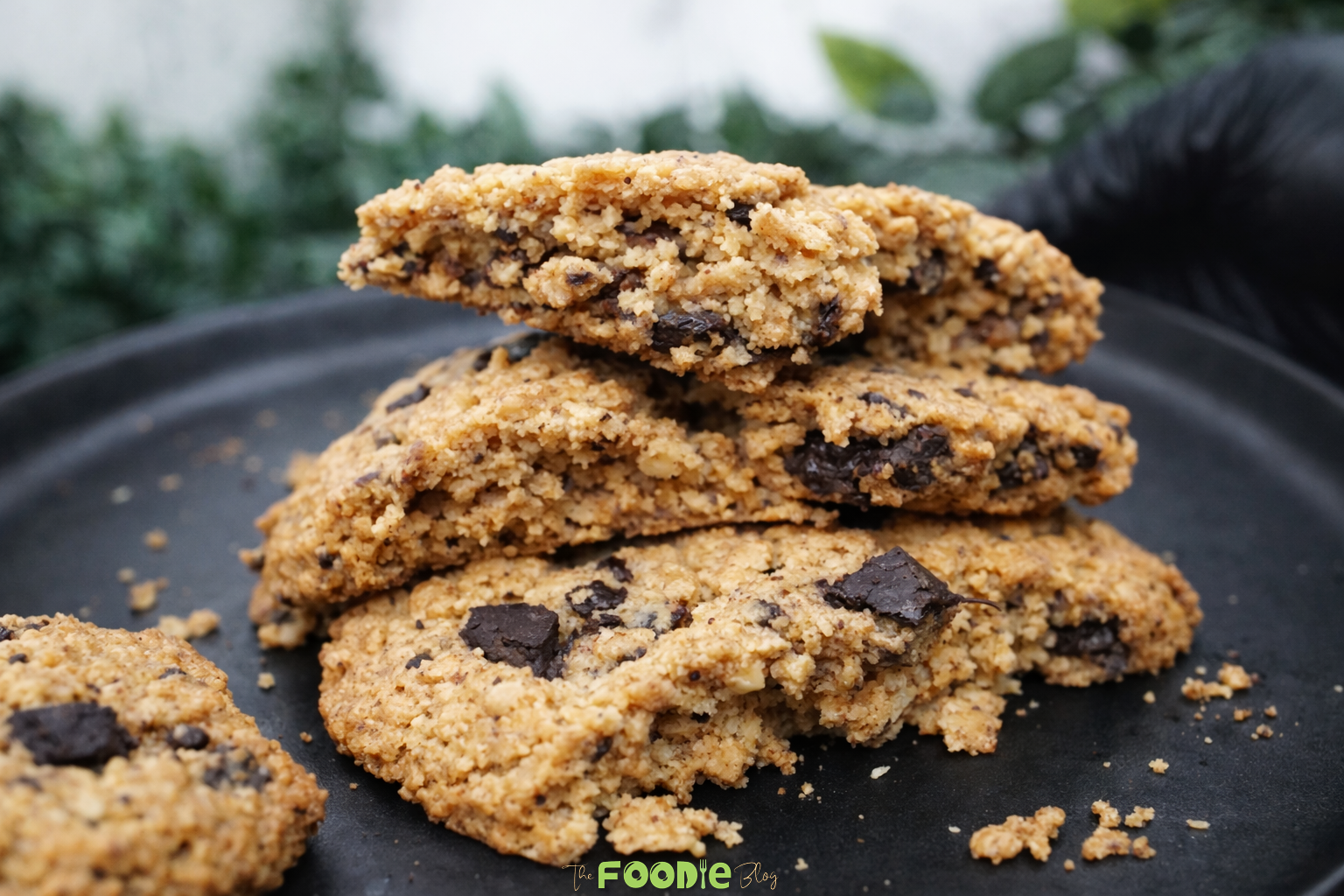 Close-up of classic walnut cookies stacked together with chopped walnuts, oats, and chocolate pieces.