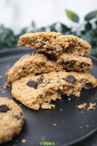 Stacked classic walnut cookies on a black plate with visible chocolate chips and a crisp golden texture.