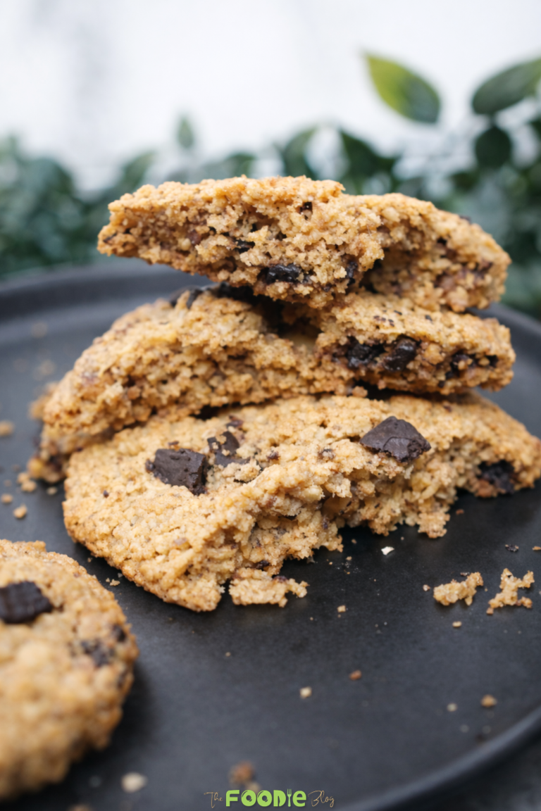Stacked classic walnut cookies on a black plate with visible chocolate chips and a crisp golden texture.