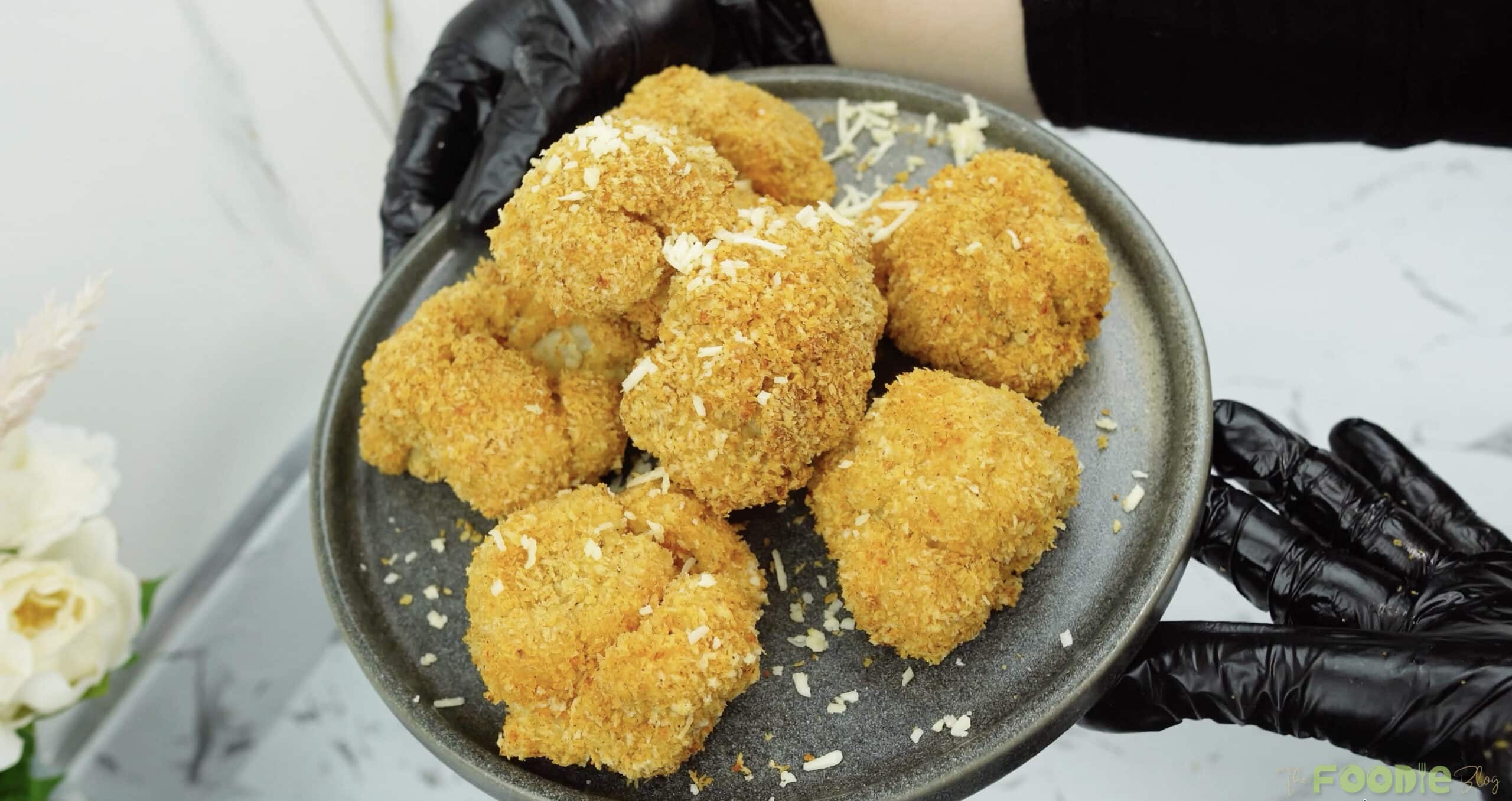 Golden breaded cauliflower bites on a gray plate, ready to serve