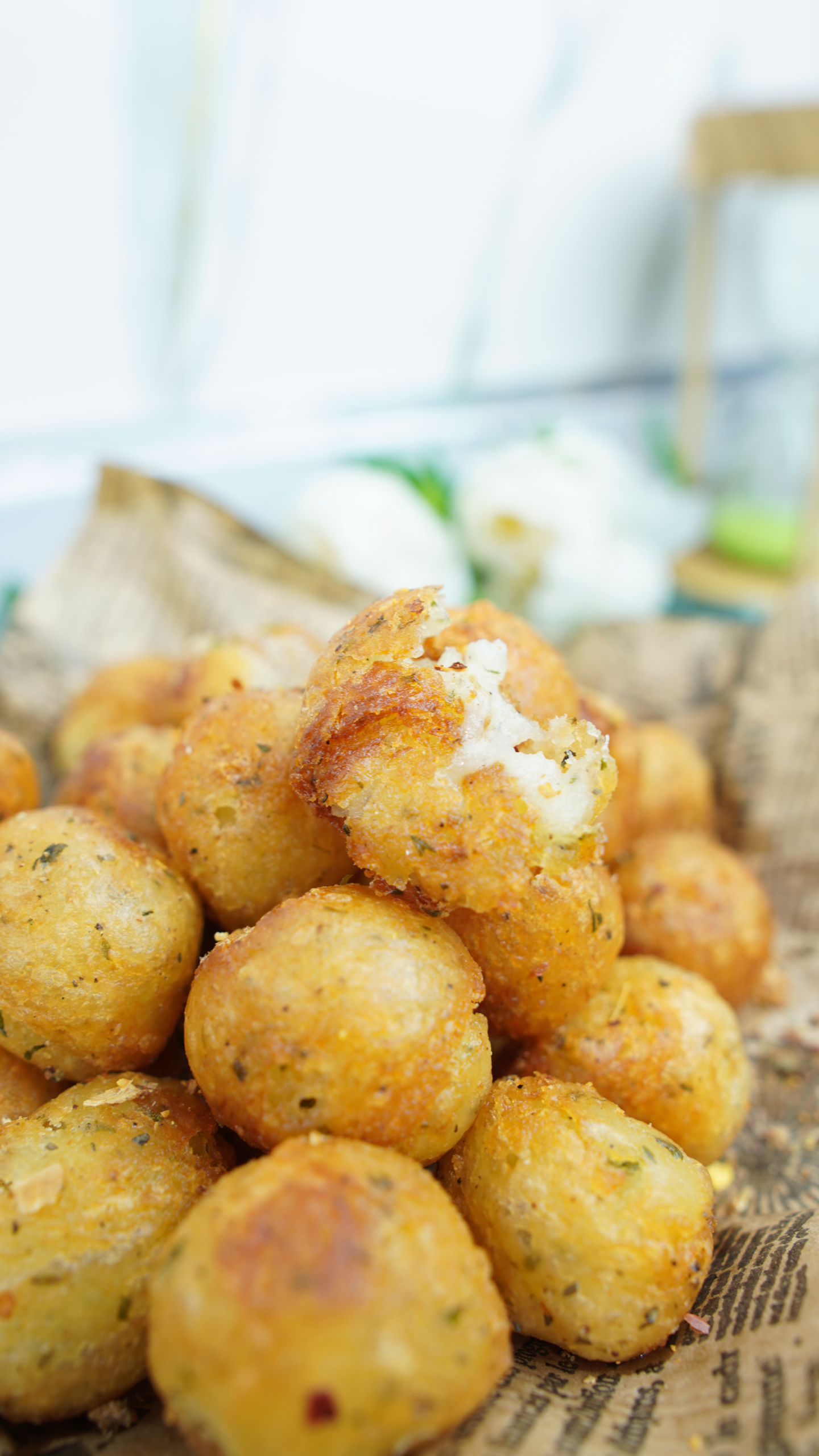 A pile of crispy potato balls with one broken open to show the fluffy inside