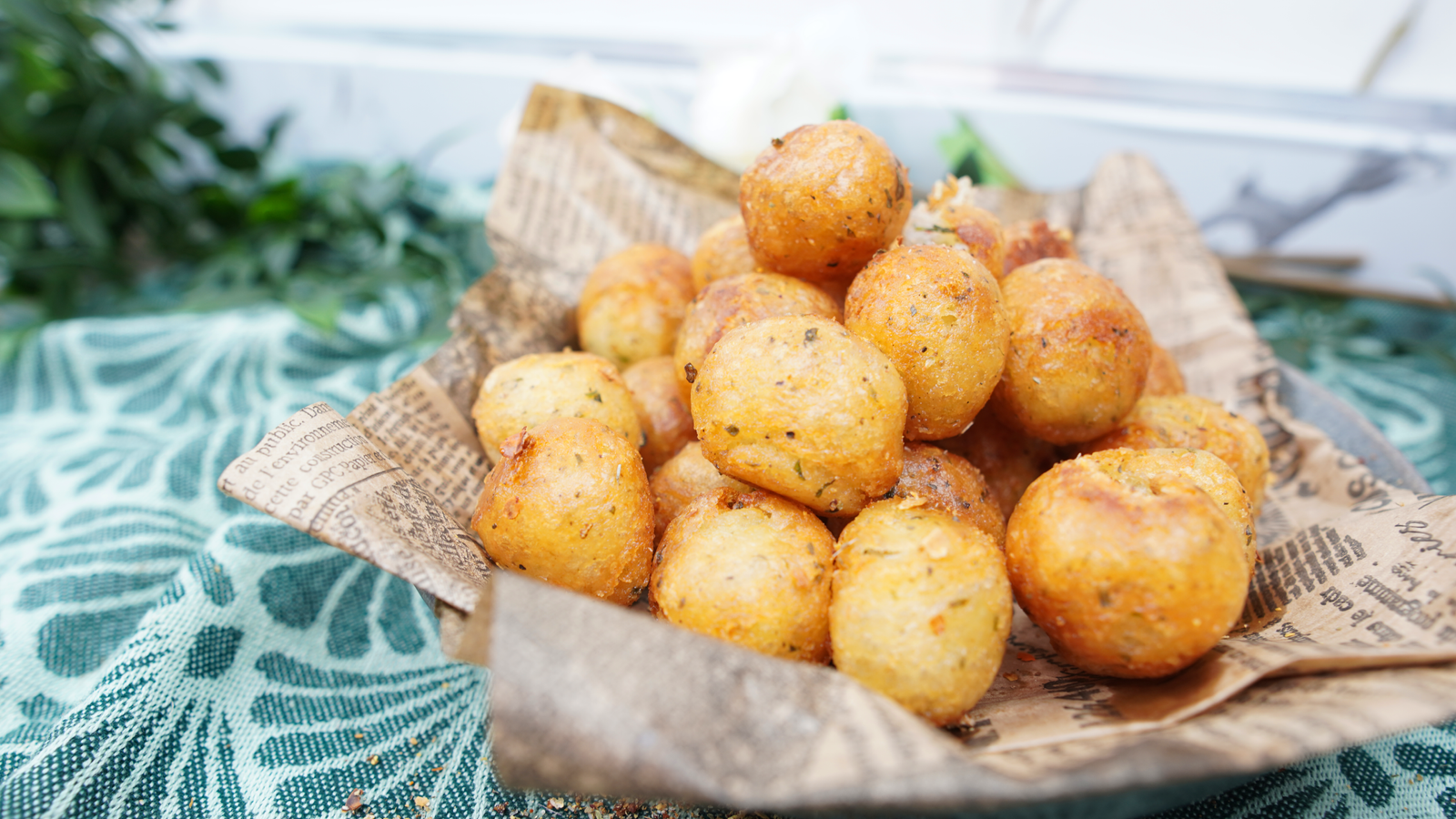 Golden crispy potato balls piled in a bowl lined with parchment-style paper